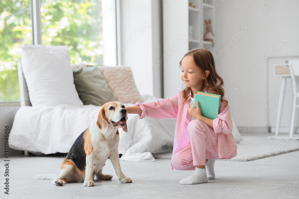 Obraz premium Cute little girl with Beagle dog and book in bedroom