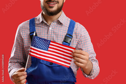 Male worker with USA flag on red background, closeup. Labor Day celebration