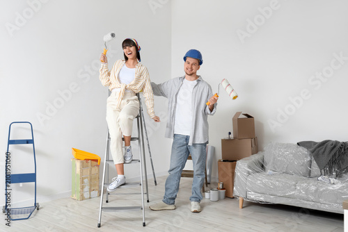 Foto Young couple with paint rollers during repair in their new house