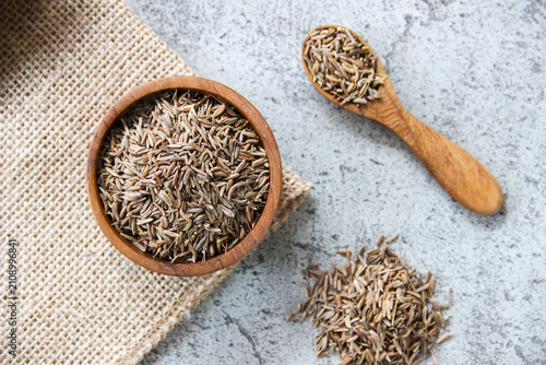 Foto Caraway seeds in wooden bowl and spoon on gray concrete background