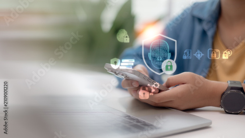 Person using smartphone with facial recognition biometric security holographic icons. Cyber security, data protection, and deepfake prevention technology concept in business.