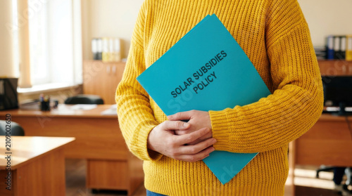 Solar subsidy policy blue folder yellow sweater office interior document folder policy concept energy subsidy renewable energy close up cropped