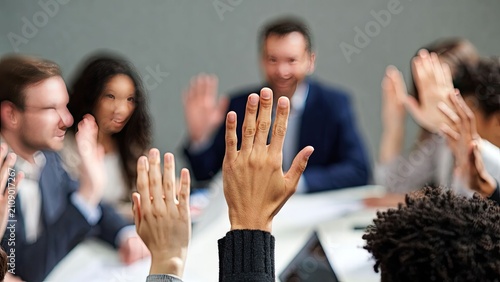 Engaged business meeting with participants raising hands to contribute ideas and share insights in a collaborative environment