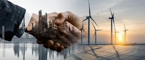 Firm handshake business deal renewable energy industrial plant wind turbine solar panel sunset double exposure partnership agreement collaboration