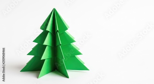 Origami fir tree made from bright green paper stands centered on a plain white surface, showcasing a modern and simple holiday aesthetic, triangular, elegant, vivid