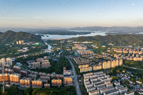Foto An aerial panorama shows an urban area with residential buildings, adjacent to mountains and a large lake, with a river running through it
