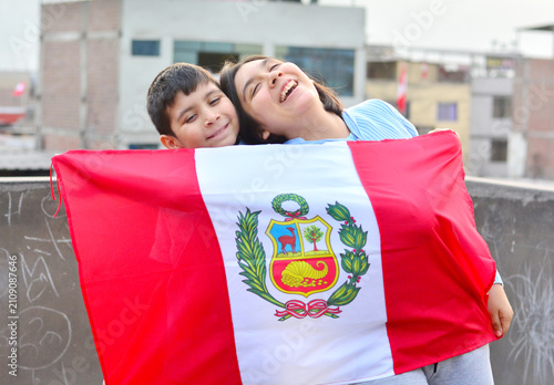 Two happy kids holding peruvian flag.