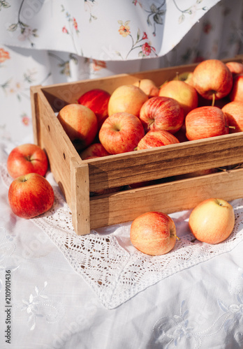 Fresh ripe red apples in wooden crate on white tablecloth rustic style