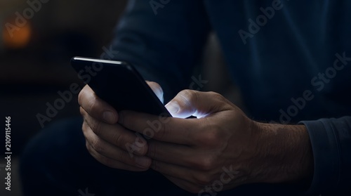 Close up of a person using a smartphone in a dark room at night.