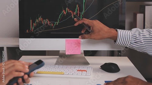 Two busy business men investors doing financial trading market data analysis. Male advisor and analyst consulting about stock exchange investing pointing at chart on laptop computer working in office.