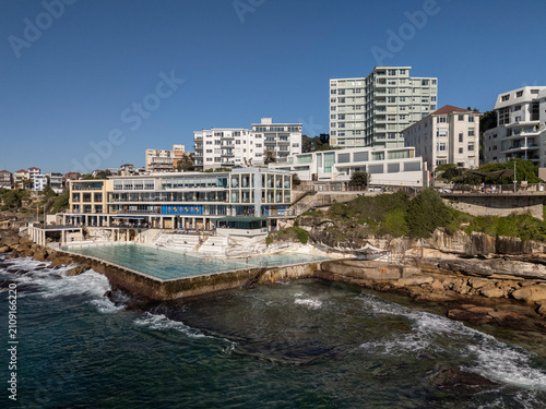 Bondi Beach on beautiful sunny day looking  over water to Icebergs pool, skyline and beachside architecture.