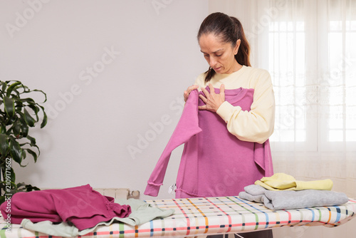 Obraz na płótnie Woman folding household laundry clothes on ironing board