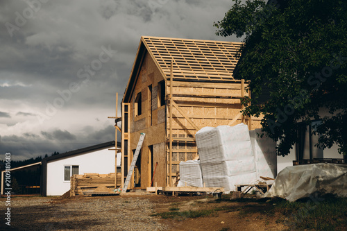 Modern wooden frame house under construction with dramatic cloudy sky