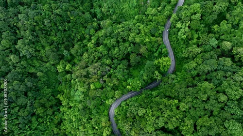 Aerial forest road with car creating abstract background for electric vehicle, ESG, sustainability and green investment business concepts.