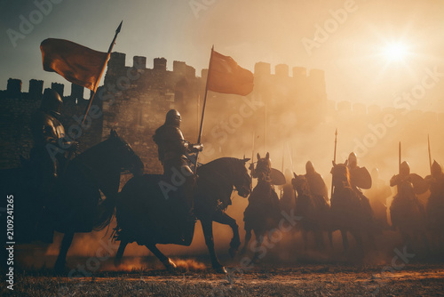 Medieval knight battle at sunset with cavalry and castle walls
