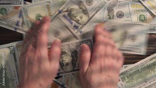 Man's hands collecting cash 100 dollar bills from table, rake in money