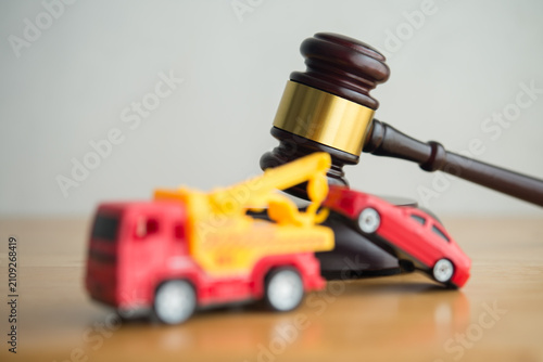 Hammer judge gavel and tow truck with car on wooden table white wall background copy space. Vehicle repossession law, bankruptcy, personal financial problem and so on concept.