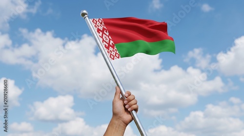 Person holding waving national flag of Belarus on silver pole against bright blue sky background