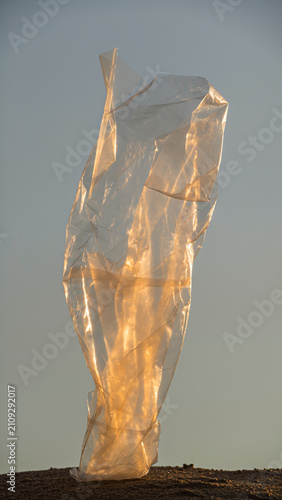 A crumpled plastic bag illuminated by sunlight against a clear sky.