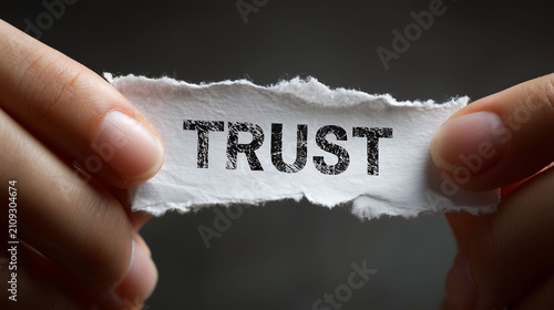 Two hands hold a torn piece of paper printed with the word 