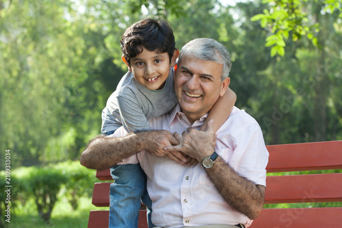 Portrait of grandfather and grandson hugging in a park