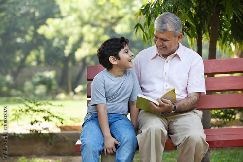 Grandfather and grandson sitting in a park