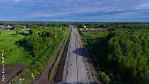 A car flies straight and high above a newly paved road on a sunny summer evening. Eastern Bypass, Novosibirsk, Russia.
