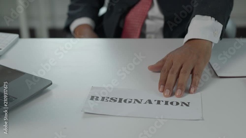 Unhappy businessman pushing resignation letter on desk