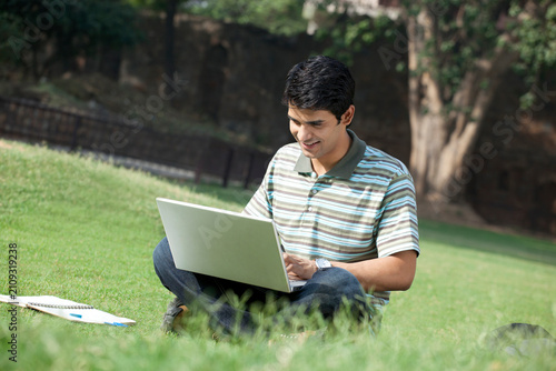 Student with a laptop sitting in a park