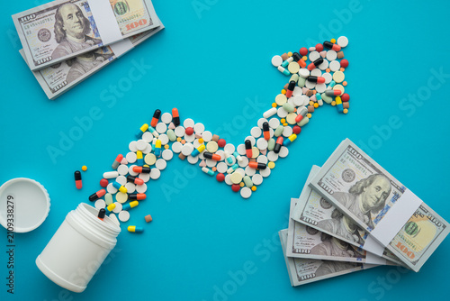 Flat lay growth pill medicine chart and US dollar bill banknotes on blue background. Medical expense rise, healthcare, cost of living increase, inflation crisis, financial planning and so on concept.