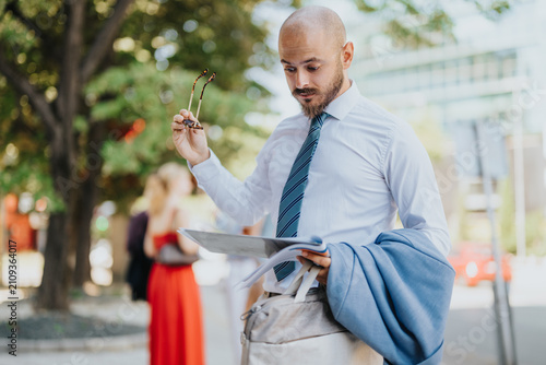 Fotografie A bald businessman in a shirt and tie reads documents while holding his glasses