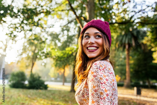 Happy young woman wearing wooly hat in a park in autumn