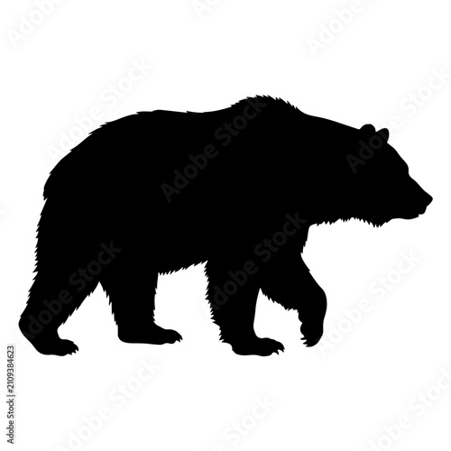 Black silhouette of a grizzly bear walking.