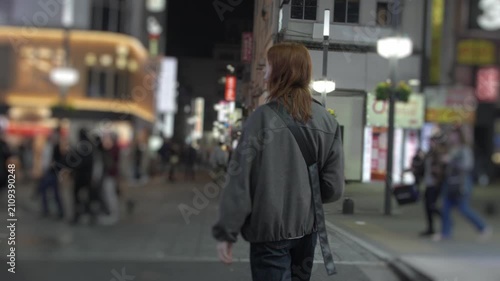 Young woman walking through a busy japanese city street at night