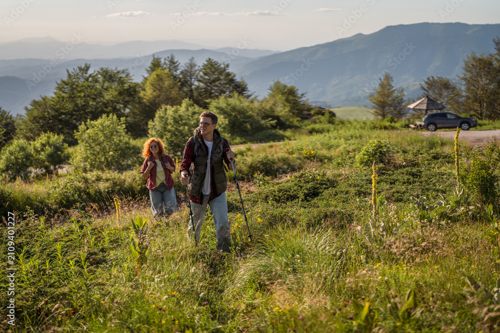 Obraz premium Couple hiking a mountain trail with backpacks and trekking poles