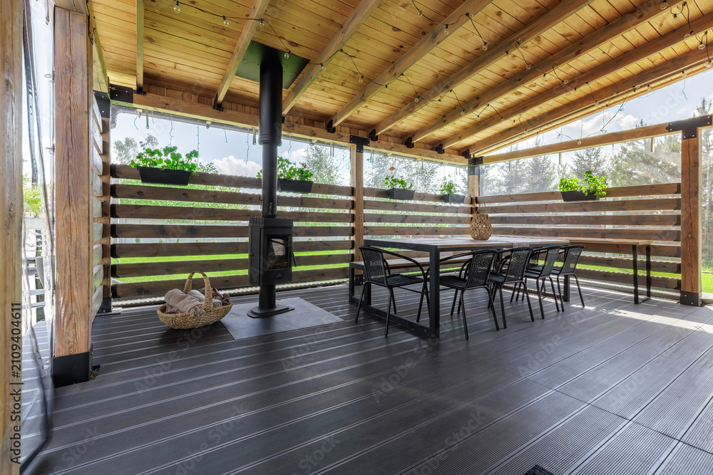 Obraz premium Wide View of Covered Wooden Terrace with Stove and Dining Area