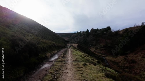 Mother and son walking on the Yorkshire Moorlands in the English countryside. Bleak barren moors or pennines. Calm lake with heather covered hills.