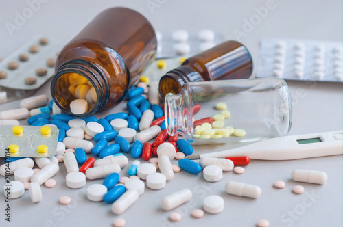 Obraz na płótnie Assorted pills spill from a medicine bottle on a clinical surface