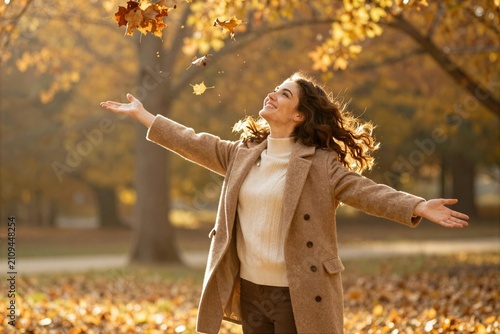 Woman enjoys autumn leaves in a park during a sunny afternoon