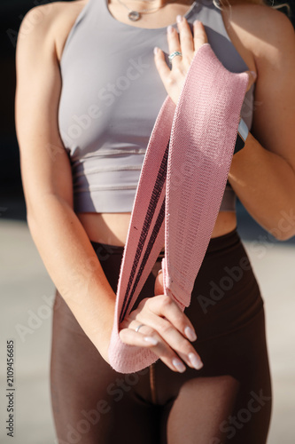 Woman holding a pink resistance band for fitness training outdoors