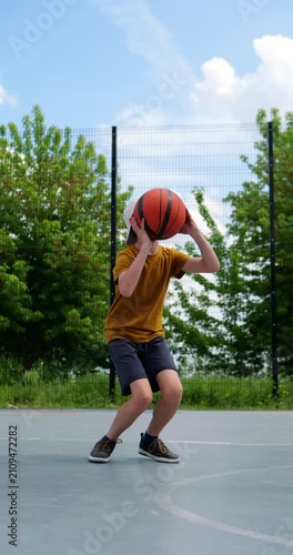 Young boy reacts with disappointment after missed basketball shot on outdoor court. Emotional childhood scene captures frustration, learning process, resilience and personal growth. Vertical video