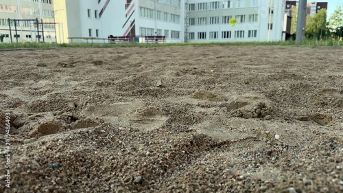 Sandy ground with footprints at school playground, outdoor area with buildings in background. School yard, playground, childhood, outdoor play