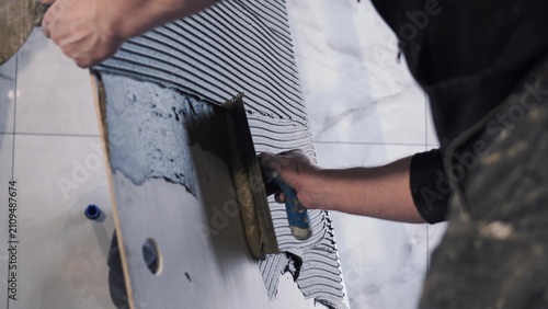 Quadro su tela Master tiler spreads glue on huge large format tiles of XXL size