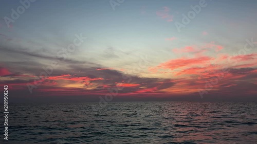 Ocean waves under colorful sunset sky with pink clouds over Maldives horizon. Concept of nature, travel, relaxation, seascape, tropical destination, peaceful atmosphere.
