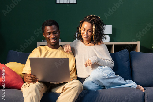 Quadro su tela Couple relaxing on couch browsing internet using laptop