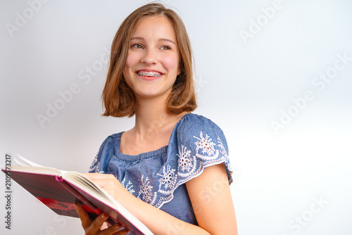 Foto young teenage girl with brown bob hair and dental braces holding open book looki