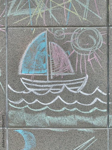 Chalk drawing of a sailboat on sea waves on grey stone tile.