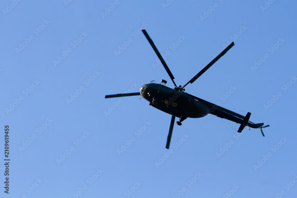 Fototapeta premium Polski wojskowy smigłowiec medyczny przelatujący tuż nad głowami na tle czystego, błękitnego nieba | Polish military medical helicopter flying overhead against clear blue sky
