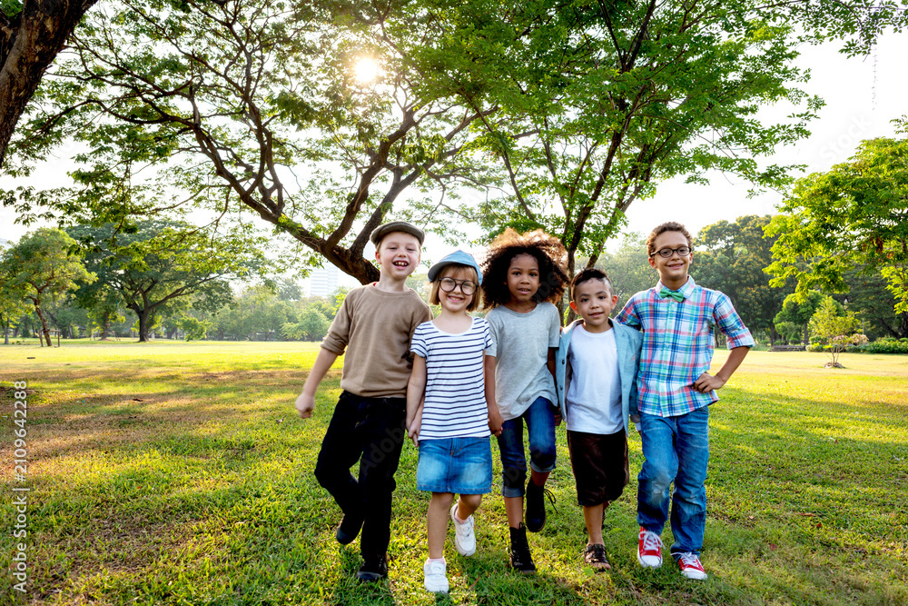 Fototapeta premium Group of diverse children smiling and walking in a sunny park.