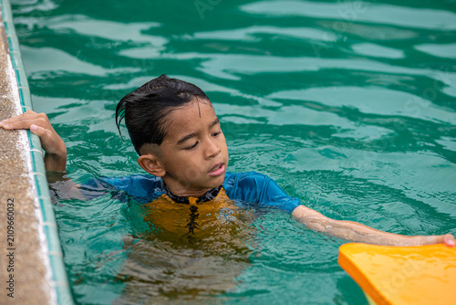 Fotografía Little asian school boy swim and buoyancy practice in swimming pool